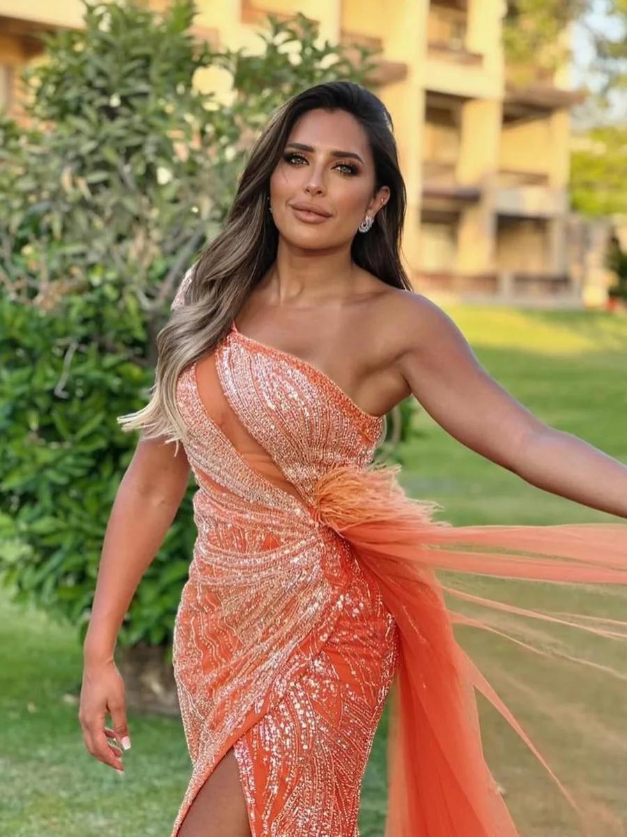 Lina, the host, in a coral evening gown.